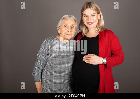 Studio Porträt der schwangeren fröhlichen Frau umarmt ältere Großmutter Stockfoto