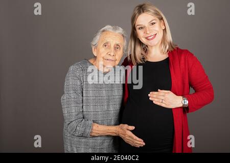 Studio Porträt der schwangeren fröhlichen Frau umarmt ältere Großmutter Stockfoto