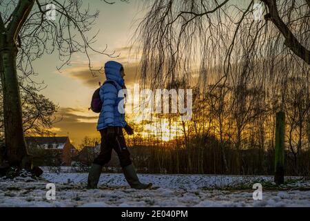 Kidderminster, Großbritannien. Dezember 2020. Wetter in Großbritannien: Mit einem zweiten Tag mit Schneeschauern in Worcestershire endet der Tag mit einem atemberaubenden Sonnenuntergang im Winter, der den Spaziergängern, die warm eingewickelt sind, ein goldenes Leuchten verleiht und die winterlichen Bedingungen in ihrem lokalen Landpark genießt. Kredit: Lee Hudson/Alamy Live Nachrichten. Stockfoto