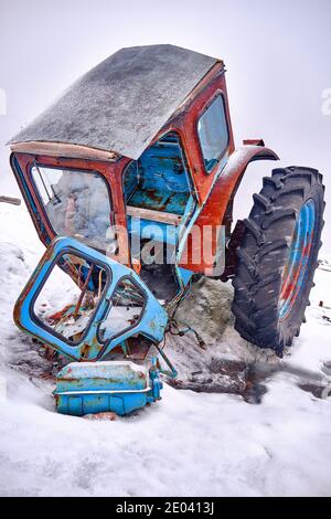 Zerlegte Teile des alten Traktors auf dem Schnee als Abfall und Verschmutzung; Konzept der Umweltprobleme Stockfoto