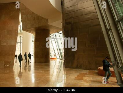 Lobby in einer Flut von Licht in der riesigen Innenraum des Guggenheim Museum, Besucher Silhouette, Kinder beobachtet Informationsbildschirm. Stockfoto