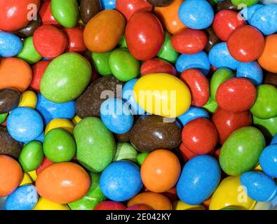 Eine Serie von mehrfarbigen, knopfförmigen Pralinen. Makro-Foto perfekt für Junk Food. Stockfoto