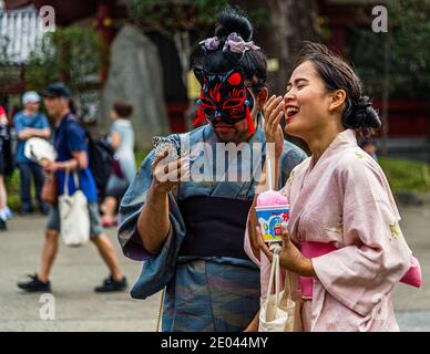 Bizarre Situation: kimono trägt ein maskiertes Paar. Straßenleben in Tokio, Japan Stockfoto