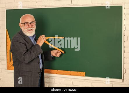 Bärtiger Tutor Mann zeichnen mit Kompass auf Tafel. Zurück zur Schule. Konzept der mathematischen grafischen Werkzeuge. In Richtung Wissen. Studieren Sie Mathematik, um gute Ergebnisse zu erhalten. Senior Mann Lehrer verwenden Kompass-Tool. Copy space. Stockfoto