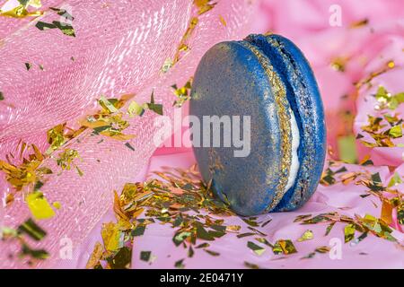 Nahaufnahme eines köstlichen blauen Makronen auf rosa Hintergrund Mit goldenem Konfetti Stockfoto