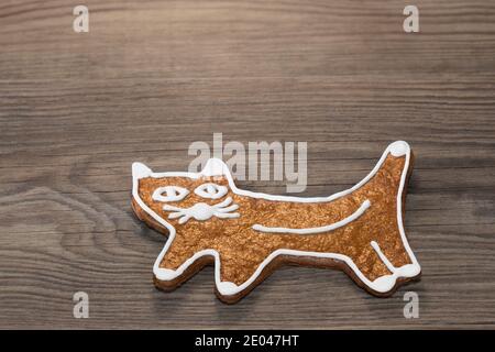 Niedliche golden gebackene Katze aus Lebkuchenkeks auf einem hölzernen Hintergrund. Schöne Weihnachten Dekoration von süßen Gebäck. Essbares Kinderspielzeug für den Kindertag. Stockfoto