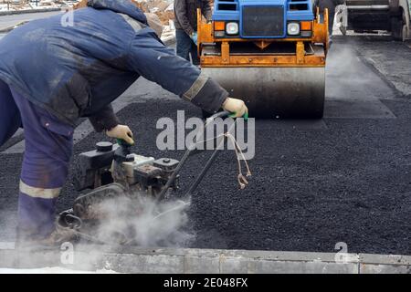 Entwicklung der städtischen Infrastruktur. Asphalt Straßenwalze mit schweren Vibrationswalze Walze Presse neuen heißen Asphalt. Neue Straßenbauarbeiten. Asphaltstraße Stockfoto