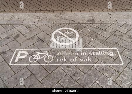 Ein Zeichen von einem Fahrrad-Parkplatz auf dem Bürgersteig in Holländisch sagt: "Nur in den markierten Plätzen oder Gestellen" Stockfoto