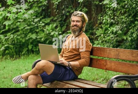 Business-Mann arbeiten im Freien mit Computer. Starten Sie Videokonferenzen. Kommunikation per Videoanruf. Geschäftsmann mit Laptop auf Bank im Park. Hübscher Mann, der am Laptop arbeitet. Mit modernen Technologien. Stockfoto