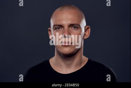 Ein Mann mit einem durchbohrten Kopf in einem schwarzen Pullover Emotionen Nahaufnahme dunklen Hintergrund Stockfoto