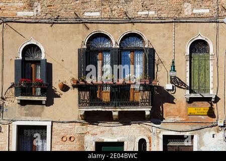 Alte traditionelle venezianische Gebäudefassade mit Balkon und hölzernen Fensterläden in Venedig, Italien Stockfoto