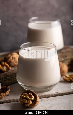 Bio Walnussnüsse und Glas Walnussmilch auf Holzgrund. Stockfoto