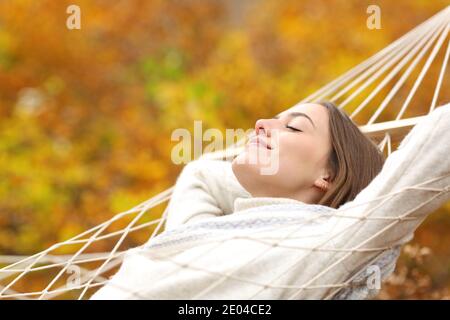 Entspannte Frau, die in der Herbstsaison im Herbst auf der Hängematte ruht In einem Wald Stockfoto