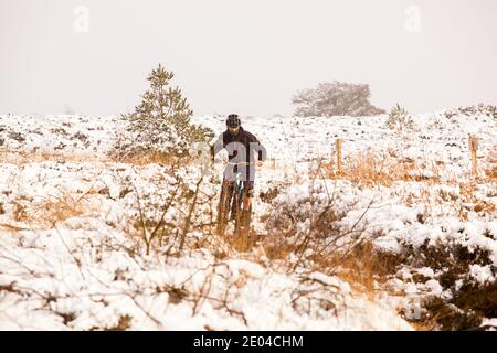 Mann auf einem Mountainbike auf verschneiten Bosley Cloud In der Nähe von Congleton Cheshire im Winter England im Besitz der Nationales Vertrauen Stockfoto