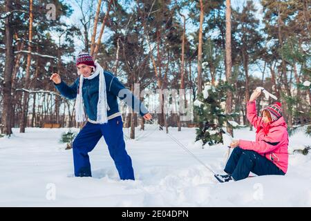 Schlitten fahren für ältere Paare. Mann, der seine Frau im Schlitten trägt. Familie Spaß im Winter Park. Aktivitäten im Freien Stockfoto