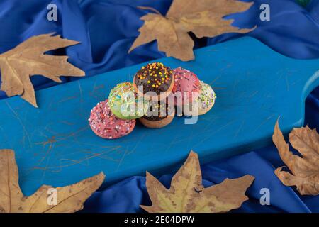 Bunte süße kleine Donuts auf einem blauen Holzbrett Stockfoto