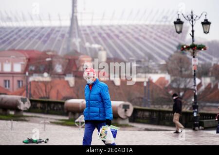Ein Mann mit Gesichtsmaske läuft am 29. Dezember 2020 mit dem Nationalstadion im Hintergrund in Warschau, Polen. Am Montag eine landesweite Quarantäne Stockfoto