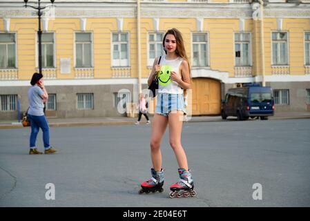 Schöne Mädchen in Shorts Fahrten auf Rollschuhe auf Palace Platz im Sommer in St. Petersburg. Stockfoto