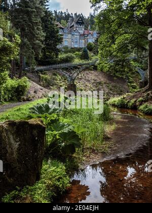 Die Eisenbrücke mit dem Haus im Hintergrund, Cragside, Northumberland zu sehen. Stockfoto