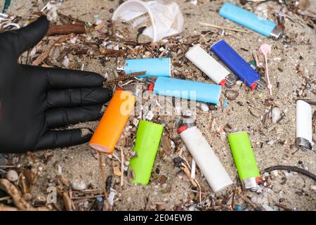 Mann sammelt Mikro-Kunststoff Feuerzeuge Abfall auf schmutzigen Ozeanküste Ökosystem, Umweltverschmutzung Stockfoto