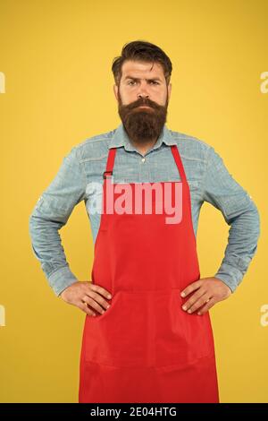 Bärtiger Mann in Koch Uniform. Reifer Verkäufer. Koch in roter Schürze. Restaurantpersonal. Hobby Kochen. Viele Liefertage Optionen. Die ganze Familie würde es genießen. Kochen zu Hause. Hilfe im Haus. Stockfoto