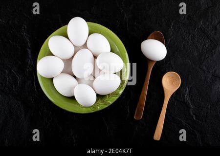 Bündel roher Eier auf grünem Teller mit Holzlöffeln Stockfoto