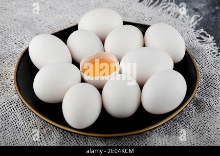 Weiße Eier und Eigelb auf schwarzem Teller Stockfoto