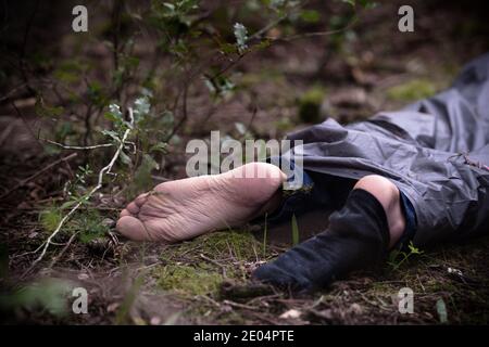 Leiche im Wald. Mordopfer auf dem Boden im Wald liegend. Ermordete Bürger, Tatort Stockfoto