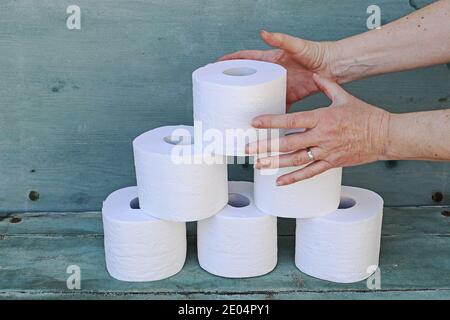 Eine Frau nimmt eine Rolle Toilettenpapier von einem Stapel. Masseneinkauf von Toilettenpapier Stockfoto