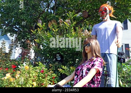 Kelly die Schaufensterpuppe sitzt, wie sie von hinten von Kevin in einer Halloween-Maske in einem Vorgarten Display gekleidet genähert wird. Stockfoto