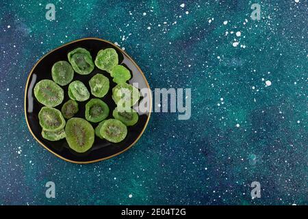 Getrocknete Kiwi-Scheiben auf schwarzem Teller Stockfoto