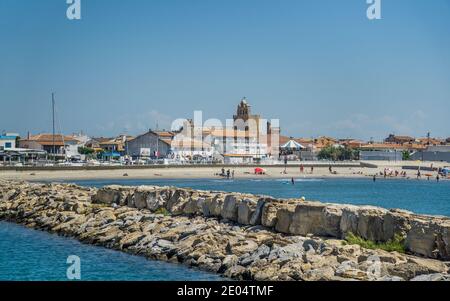 Hafendamm von Port Saintes-Maries-de-la-Mer mit Blick auf den Strand Arena und die befestigte Kirche im Hintergrund, Departement Bouches-du-Rhône, Sou Stockfoto