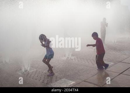 Bei heißem Wetter spielen Kinder in den Wasserfontänen in Mexiko-Stadt, Mexiko Stockfoto