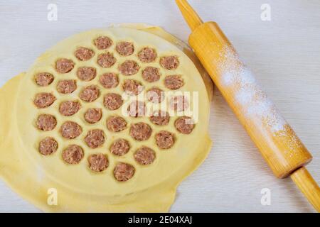 Prozess der Herstellung von Ravioli, Pelmeni oder Knödel Fleisch auf Holztisch in der Küche. Stockfoto