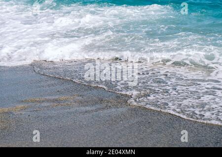 Weiße, schäumende Wellen am Sandstrand in der Nähe. Stockfoto