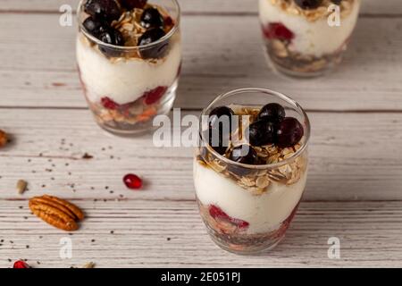 Schräg Blick auf köstliche Obst Joghurt Parfait Tassen gefüllt mit Schichten von Müsli, Chiasamen, frische Beeren, Haferflocken und hausgemachtem Joghurt serviert w Stockfoto
