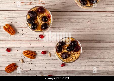 Flaches Bild von köstlichen Fruchtjoghurt Parfait Tassen gefüllt mit Schichten von Müsli, Chiasamen, frische Beeren, Haferflocken und hausgemachtem Joghurt serviert Stockfoto