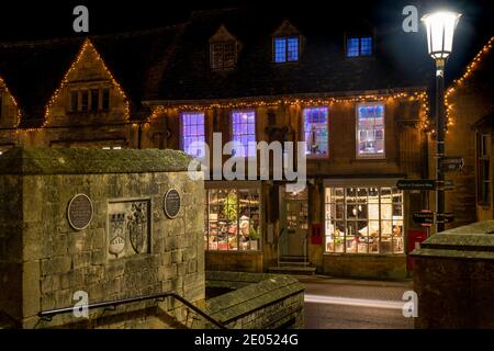 Chipping Campden High Street Shop mit weihnachtsbeleuchtung und Dekorationen in der Dämmerung. Chipping Campden, Cotswolds, Gloucestershire, England Stockfoto