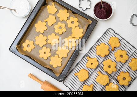 Rezept für mit Marmelade gefüllte Shortbread-Kekse. Frisch gebackene Plätzchen aus der Nähe auf Kühlregal, flach legen Stockfoto