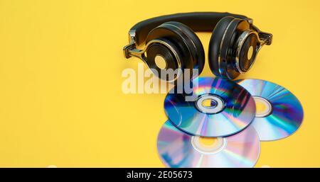 Kopfhörer und Musik-Discs auf gelbem Hintergrund. Musikalisches Konzept. Stockfoto