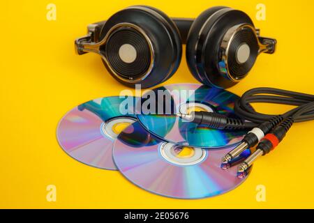 Kopfhörer und Musik-Discs auf gelbem Hintergrund. Musikalisches Konzept. Stockfoto