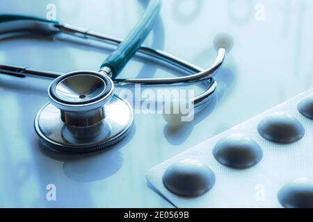 Stethoskop und Pillen mit Reflexion und blauer Färbung. Stockfoto
