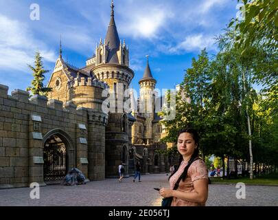 Khryashchevka, Russland, 16. Juli 2020, Garibaldi Burg, Casual junge Frau geht vor einem modernen Hotel stilisiert wie ein mittelalterliches Schloss Stockfoto