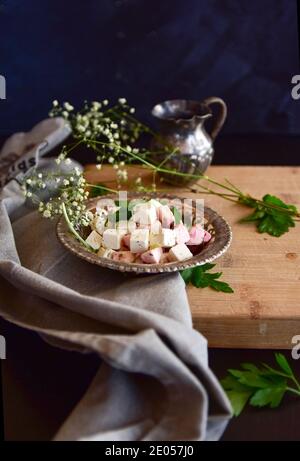 Eine Schüssel mit Feta-Käse mit Kräutern auf einem Holztisch auf schwarzem Hintergrund. Stockfoto