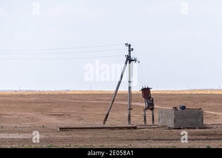 Trafostation in der Nähe einer Säule in Steppe. Stromleitungen in ländlichen Gebieten. Elektrische Generatoren an die Leitung angeschlossen. Stockfoto