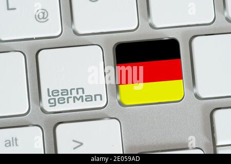 Ein Computer, eine Flagge Deutschlands und Deutsch lernen Stockfoto