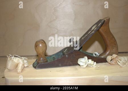 Eine alte Hand Wagenheber Flugzeug auf einem Holztisch, neben einem Holzsägemehl in der Werkstatt. Tischlerwerkzeuge. Stockfoto