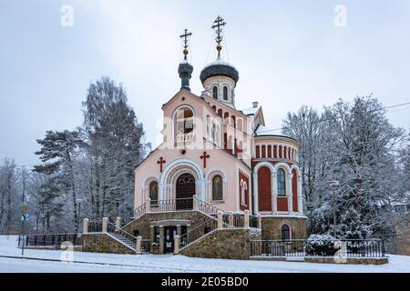 Marianske Lazne, Tschechische Republik - Dezember 29 2020: Winteransicht der orthodoxen russischen Kirche St. Vladimir mit roter Fassade umgeben von Bäumen Bucht Stockfoto