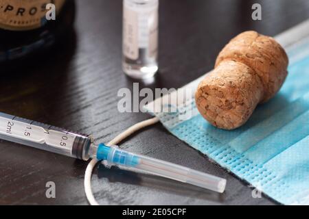 Spritze, Fläschchen, chirurgische Gesichtsmaske, Flasche und Kork. Neujahr Konzept während Covid19 oder Coronavirus Notfall, keine Partei Stockfoto