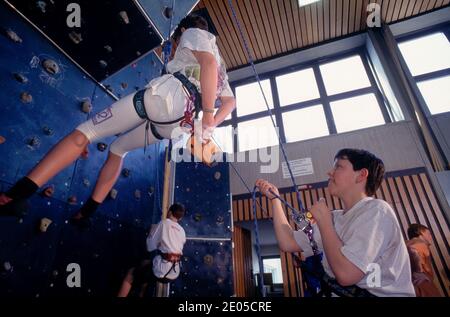 Jungs klettern an einer Indoor-Kletterwand Stockfoto